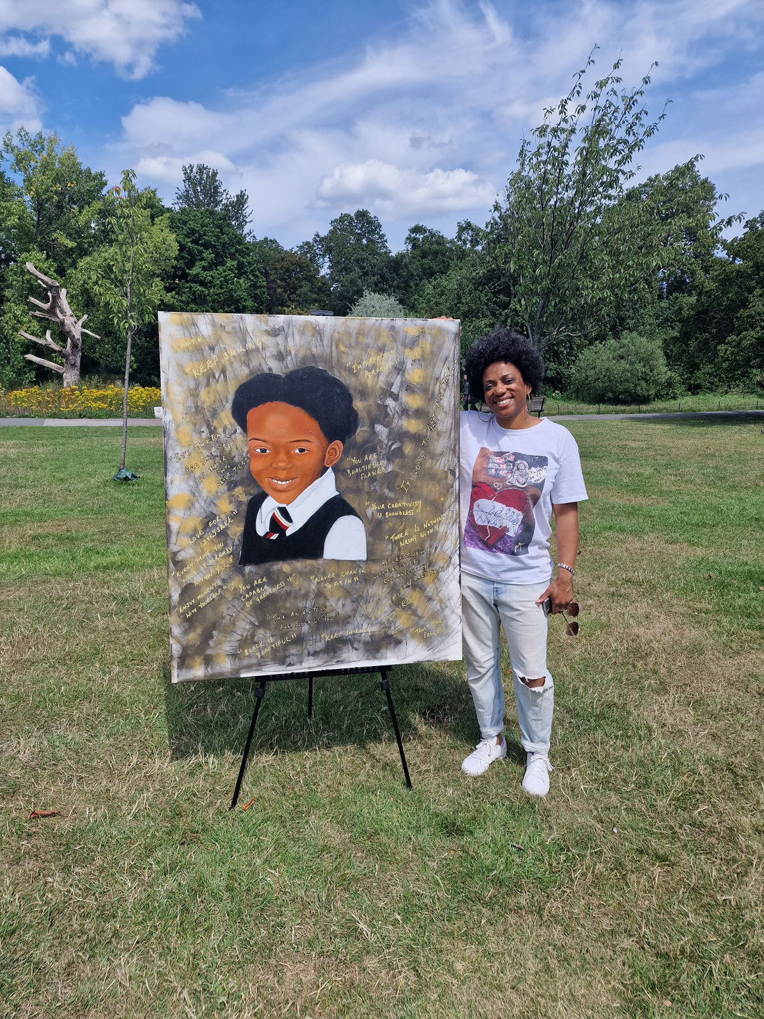 Antonia (Amja) Lee beside her Original contemporary artwork of a young black girl surrounded by gold affirmation of self-love and pride. 