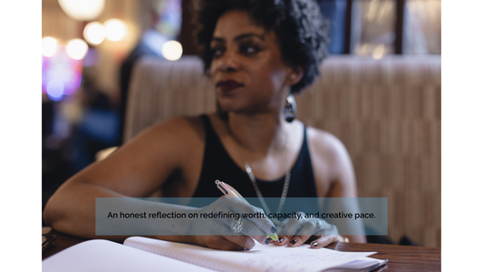  Antonia Amja Lee writing reflectively at a table, representing capacity, creative pacing, and self-worth in artistry and strategy.